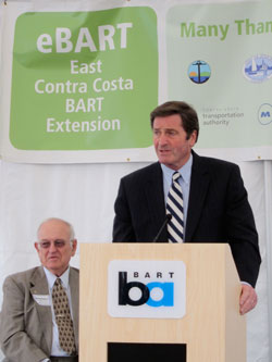 BART Director Thomas Blalock, seated, and Representative John Garamendi at the lectern.