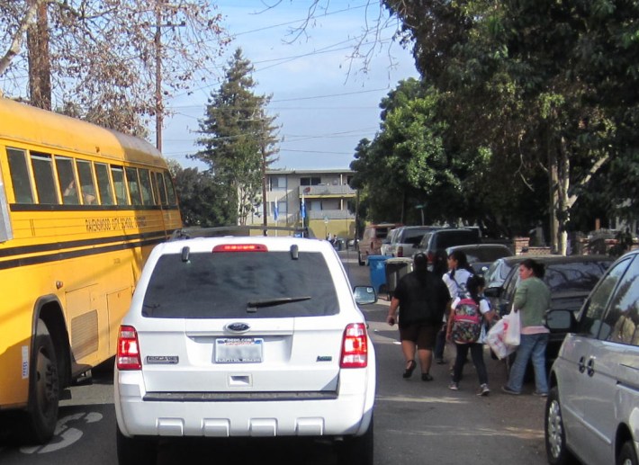 Children walking home from school share the road with vehicles on Scofield Avenue in East Palo Alto, where the city plans to install sidewalks where none exist today. Photo: Andrew Boone