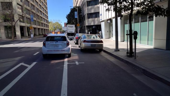 Oakland Parking Enforcement parking in the bike lane right in front of an open spot. Image: Streetsblog.