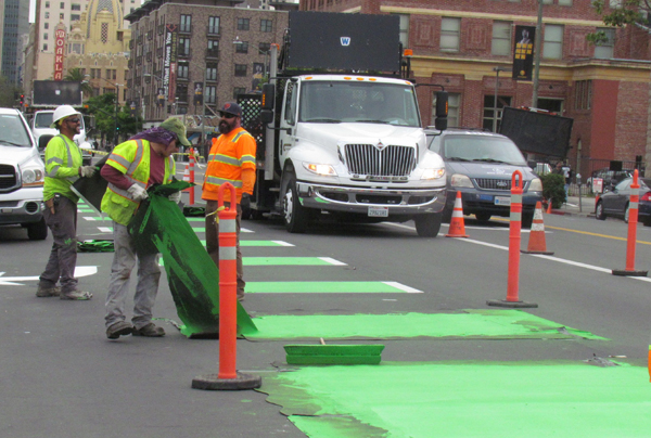 Workers pull up stencils on green lane markings. All photos: Melanie Curry/Streetsblog