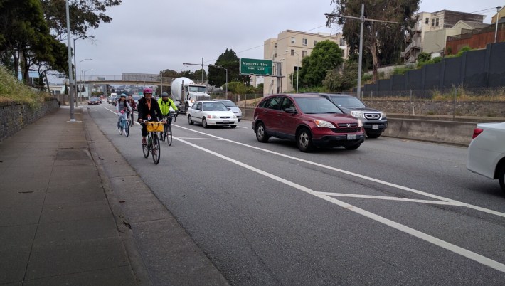 Wide, buffered bike lanes help make cycling safer and more comfortable, although it's unclear why the protection bollards don't continue the whole way. Photo: Streetsblog.
