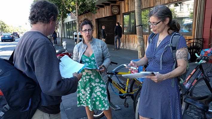 Catherine Orland (green dress) in 2016, when she lead volunteers counting the number of cars blocking bike lanes on Valencia. Photo: Streetsblog.