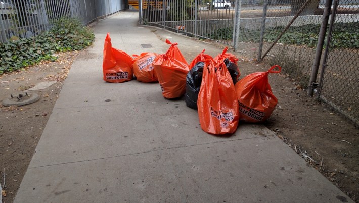 Caltrans workers piled trash bags on the east bound bike path. Photo: Streetsblog.