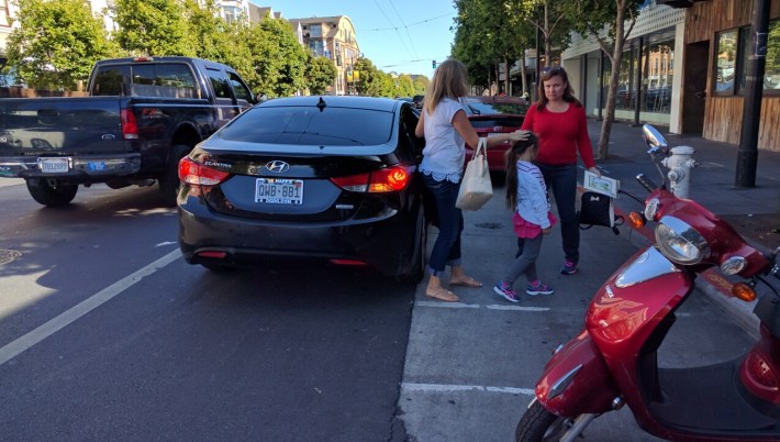 A car discharging passengers on Valencia. Will a new education campaign get ride-hails out of the bike lane? Photo: Streetsblog