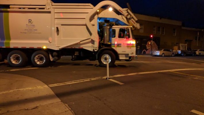 A garbage truck is forced to make a slow, careful turn, rather than sweeping the corner and potentially running over a cyclist in its "blind" spot. Photo: Streetsblog