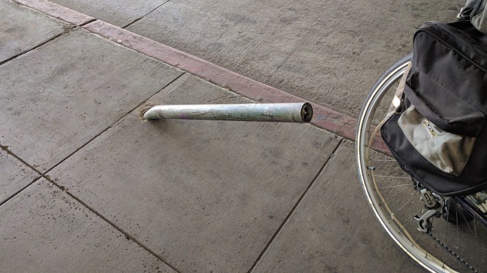 This bent pole on the sidewalk under MacArthur BART says volumes about the dangerous road conditions. Photo: Streetsblog/Rudick