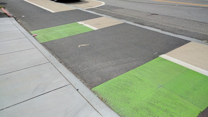 The driveways across the bike lane are smooth and level for cars, inviting conflicts. Photo: Streetsblog/Rudick