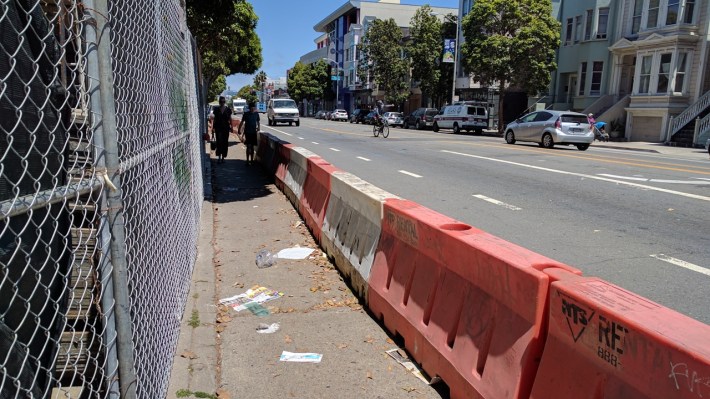 Temporary crash barriers protect people walking past a construction site on Valencia...but the bike lane is forgotten. Photo: Streetsblog/Rudick