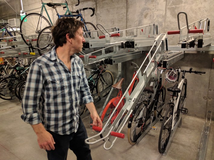 Lemieux demonstrates a double-decker bicycle lift rack, with springs to assist people in getting bikes onto the upper shelf. Photo: Streetsblog/Rudick
