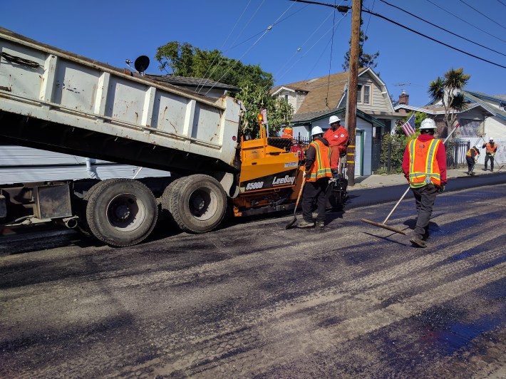 A dump truck loads asphalt into the new spreader