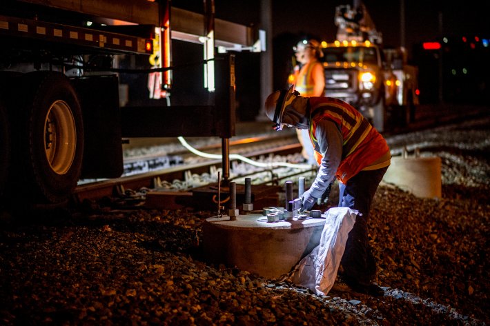 A construction worker finishing up a electric pole foundation on Caltrain's mainline on the Peninsula, pre-COVID. Image: Caltrain