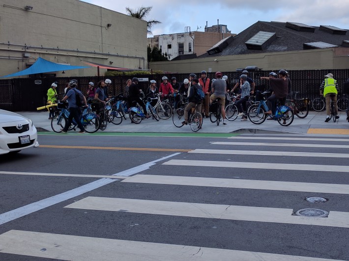 The group assembled at the one short segment of protected bike lane on Valencia to discuss ways to get it extended down the length of the street