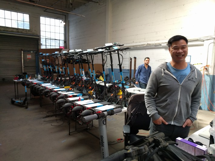 Co-founder Tran with scooters undergoing modifications to work with the Skip system