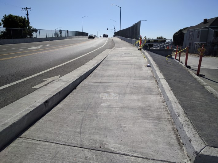 After passing through a series of long waits at staged pedestrian crossing with long-wait beg buttons, a pedestrian finally gets to this sidewalk--one side only.