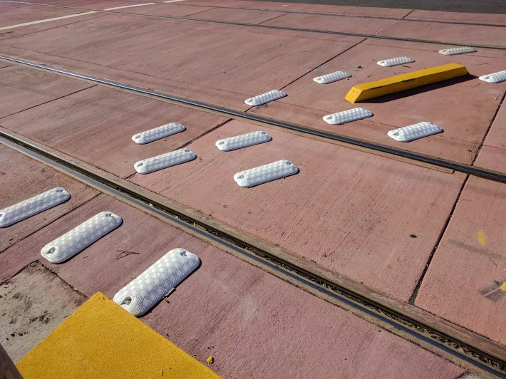 Muni added colored pavement and more treatments to help keep cars off the tracks where they leave 19th Ave.