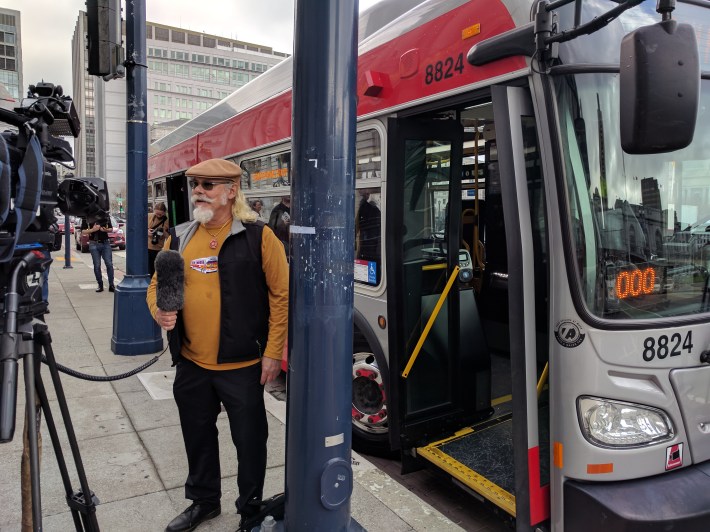 Arthur Koch doing a television interview in front of an SFMTA "Art Bus" parked in front of the event at City Hall this morning
