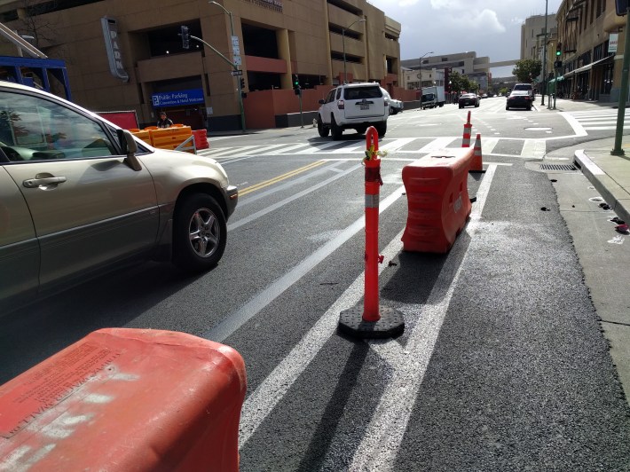 Cars are physically stopped from violating this bike lane by still-temporary, but immovable barriers