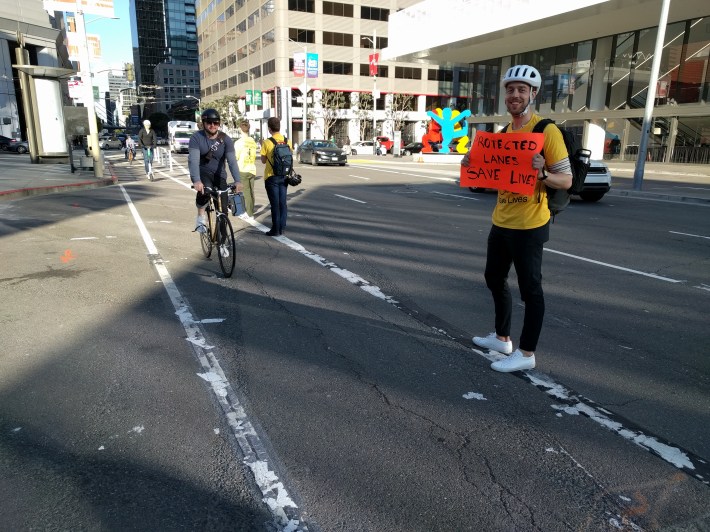 Bill Couch, seen holding the sign, was hit while riding his bike on Valencia