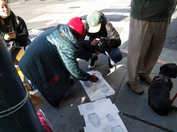 Protesters at a vigil held in May, painting "ghost feet" where a man was run down by a bus in the Tenderloin. Photo: Streetsblog/Rudick