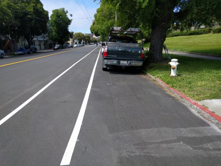 Even along the park, business as usual, with a door-death bike lane