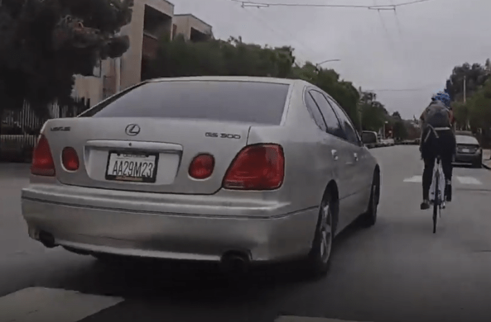 A still from the video of a motorist intentionally ramming a cyclist on McAllister... the number on the dealer plate is clearly visible