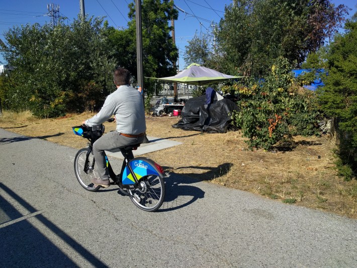 A rider on the tour passing one of many encampments along the route