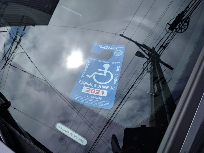 This car was parked at an unpaid meter with this disabled placard and dealer plates.