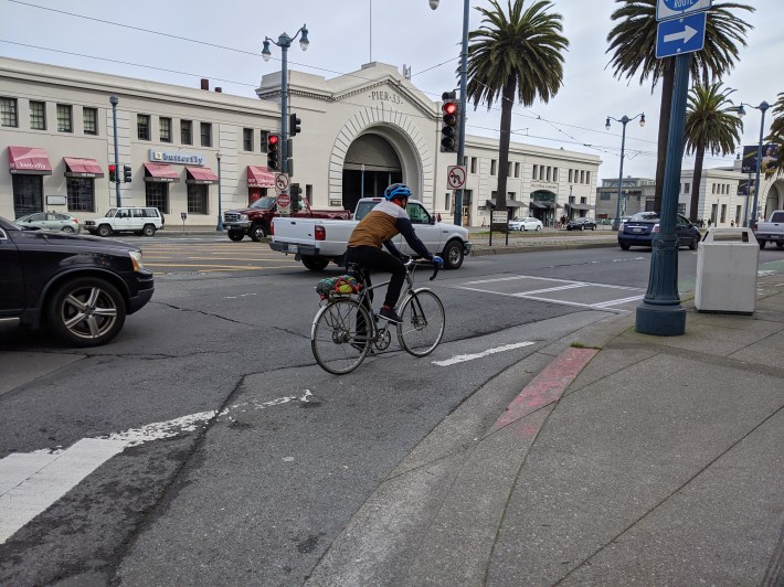 A cyclist navigating southbound with not so much as a drop of paint through the high-speed intersection with Bay. Photo: Streetsblog/Rudick
