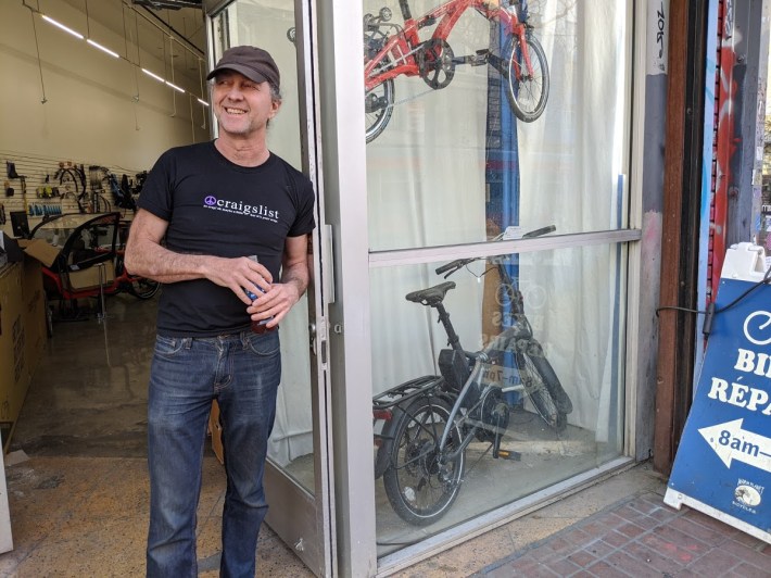 Kash Haas, owner of Warm Planet Bikes on Market, in front of his shop watching cyclists go by. Photo: Streetsblog/Rudick