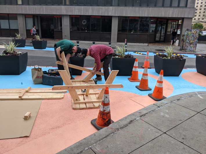 Workers finishing up picnic benches for the 13th St. Commons