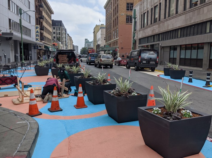 Planters and paint narrows the street down to one lane, for loading and to allow access to a garage