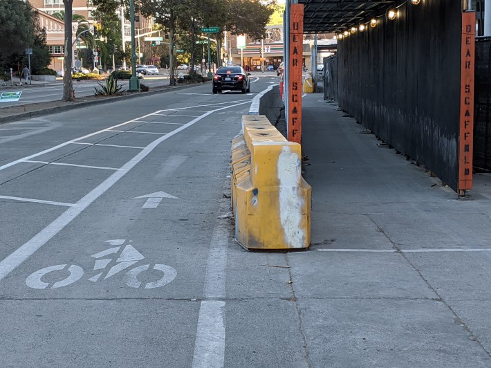 A more typical construction zone treatment that forces cyclists to deal with traffic and illegally parked cars