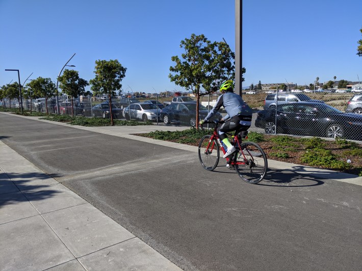 A cyclist exploring the new park, riding past the vast parking lots