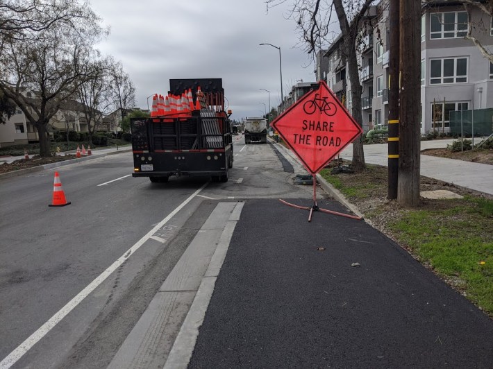 A raised bike lane project in Fremont, 2020. Instead of using colorized asphalt, Fremont put in fresh conventional asphalt and then came back later to paint it. Photo: Streetsblog/Rudick