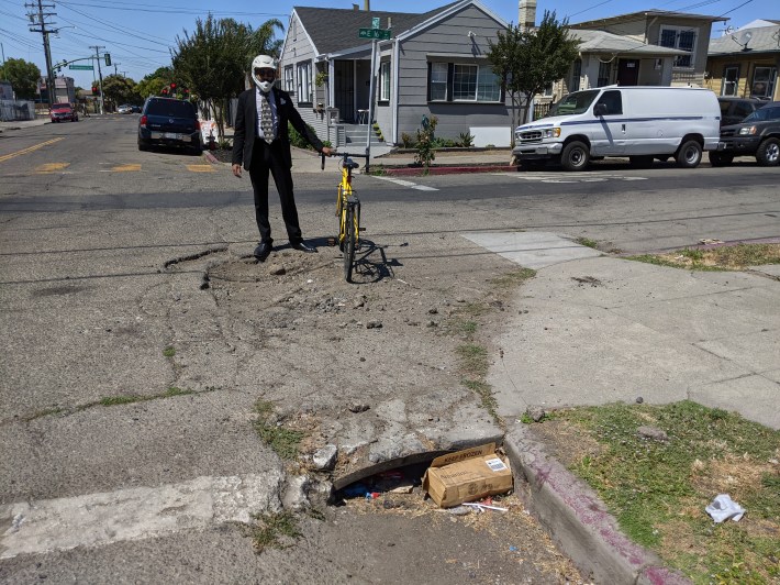 Swaminathan looking at a bad drain in East Oakland (he wears a full-face helmet when cycling because of a bad fall a while back).