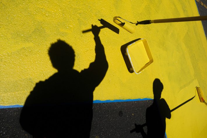 Community members gather to help repaint the mural.