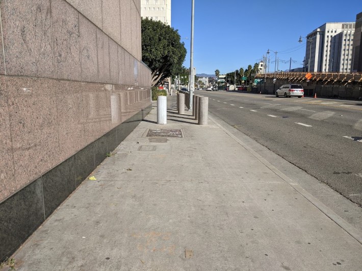 Pedestrians walking from Little Tokyo to Union Station are forced onto this one narrow sidewalk, through an obstacle course of concrete bollards. Photo: Streetsblog/Rudick