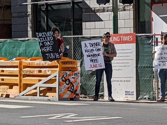 Two demonstrators standing next to the sled that's part of the barrier to protect the construction sight from errant motorists. Photo: Streetsblog/Rudick