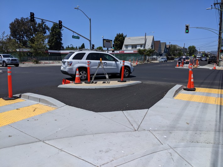 A motorist taking the corner at West and MacArthur at a protected intersection partially funded by KK. Photo: Streetsblog/Rudick