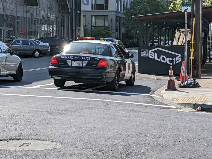 An Oakland cop hanging out on the bike lane, blocking the daylighting. Photo: Streetsblog/Rudick