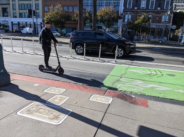 A scooterist on the protected bike lane on the Embaradero